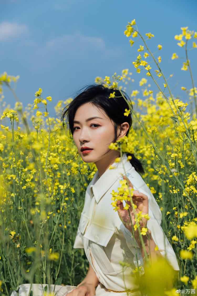 万茜晒照承包油菜花田 穿白衣浅笑温柔迷人